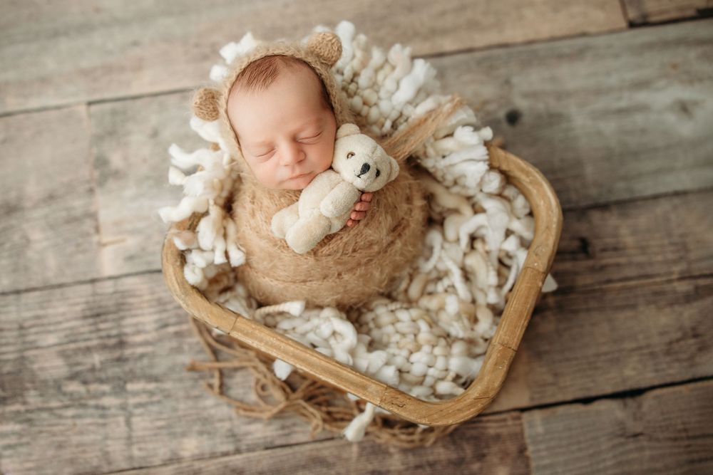 A collection of newborn photography setups with soft white props and wooden textures in a rustic style.