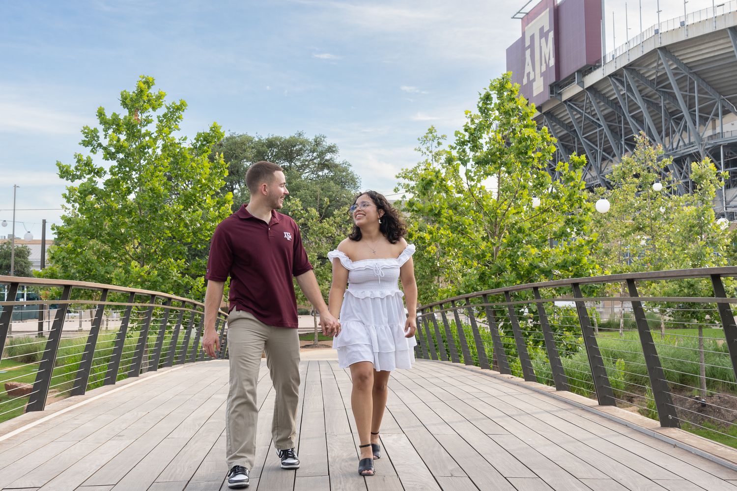 Aggie couple walking on the bridge by Kyle Field. College Station engagement photography by Isaac Killgore in Bryan-College Station, TX.