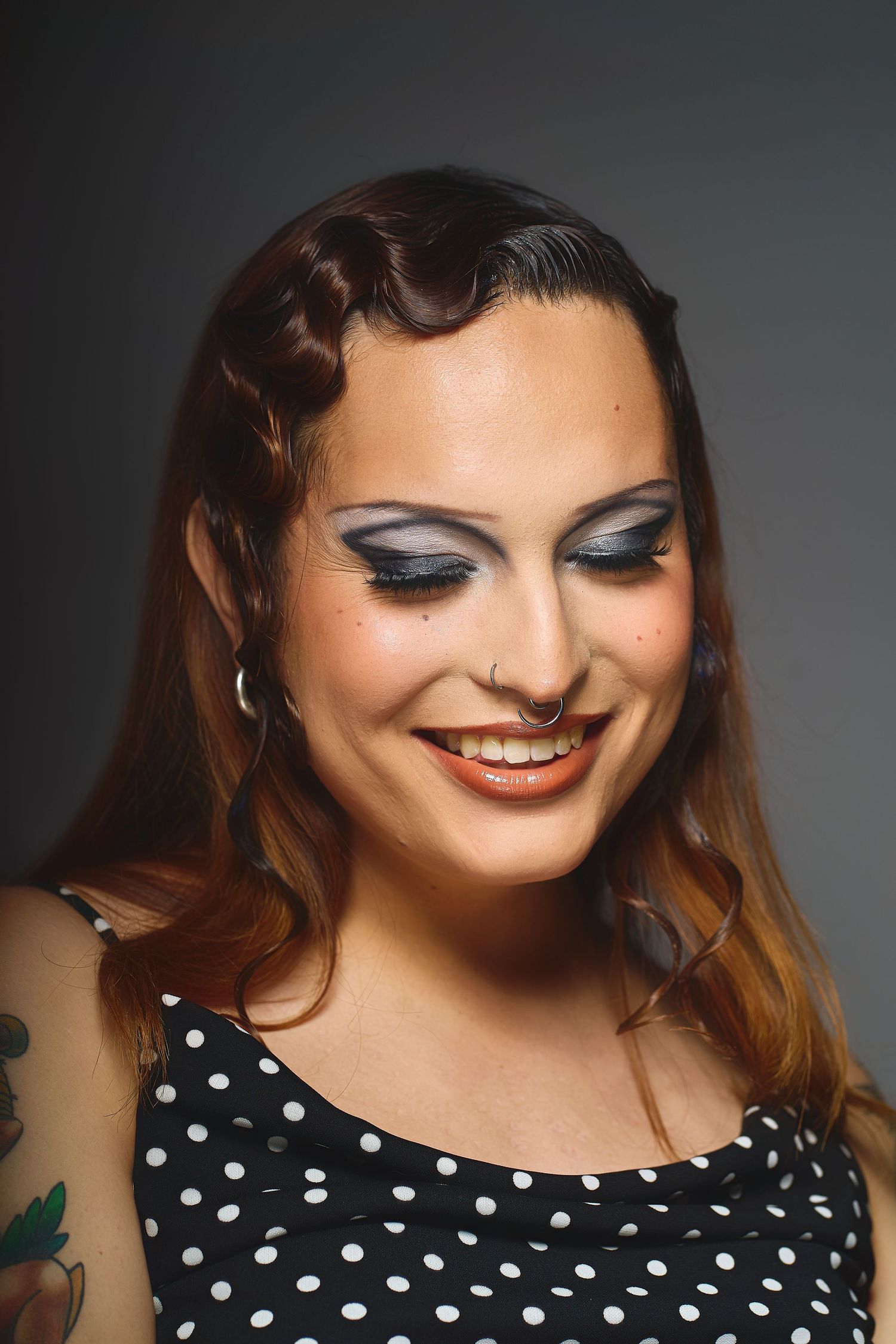 Beauty shot of a smiling woman with retro pin-up hairstyle, dramatic smoky eye makeup taken at an Oakland photography studio.