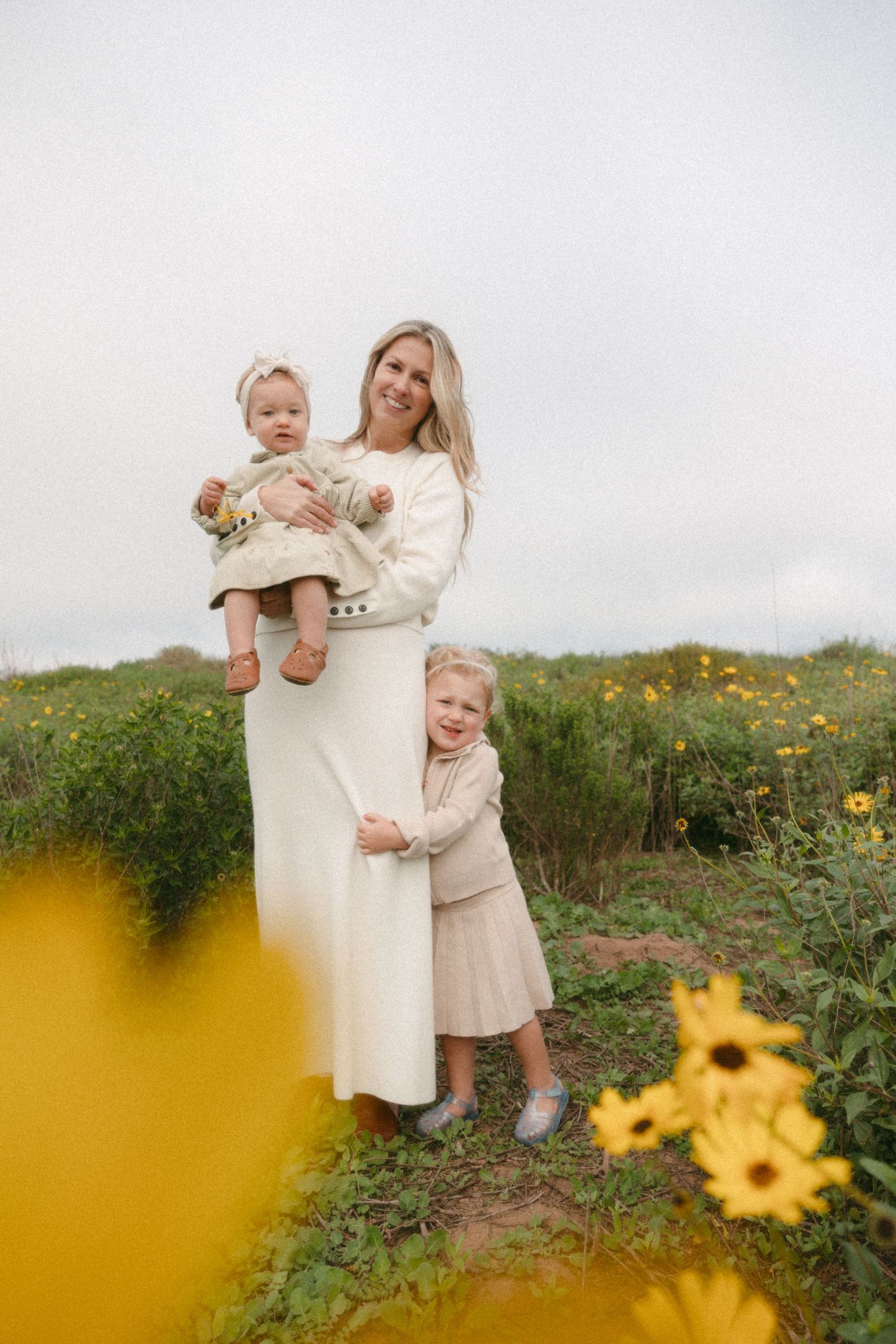 Candid family moments captured in a field of yellow wildflowers on a cloudy day.