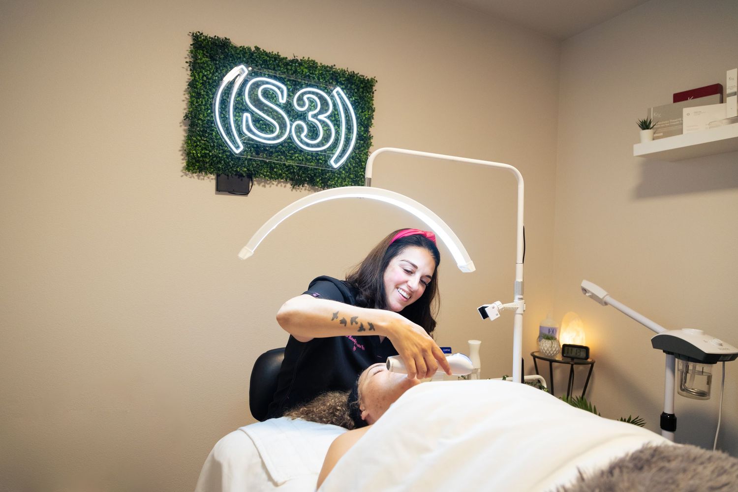 A nail technician in a black uniform applies polish during a professional manicure service at a salon.