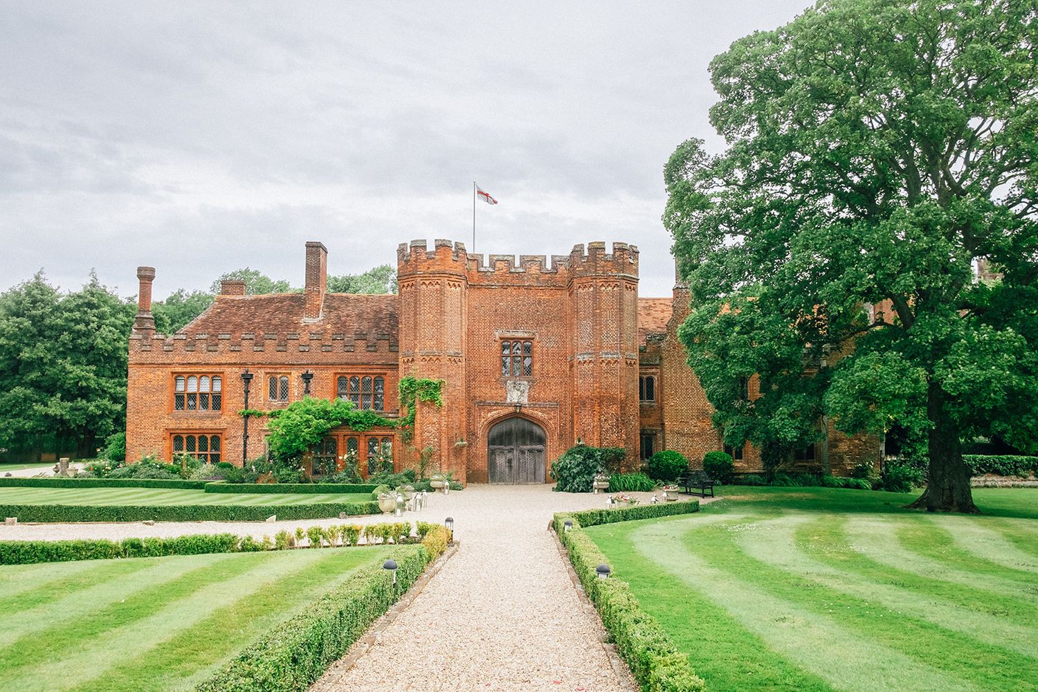 Wedding celebration with guests throwing confetti outside a historic castle with brick towers and turrets.