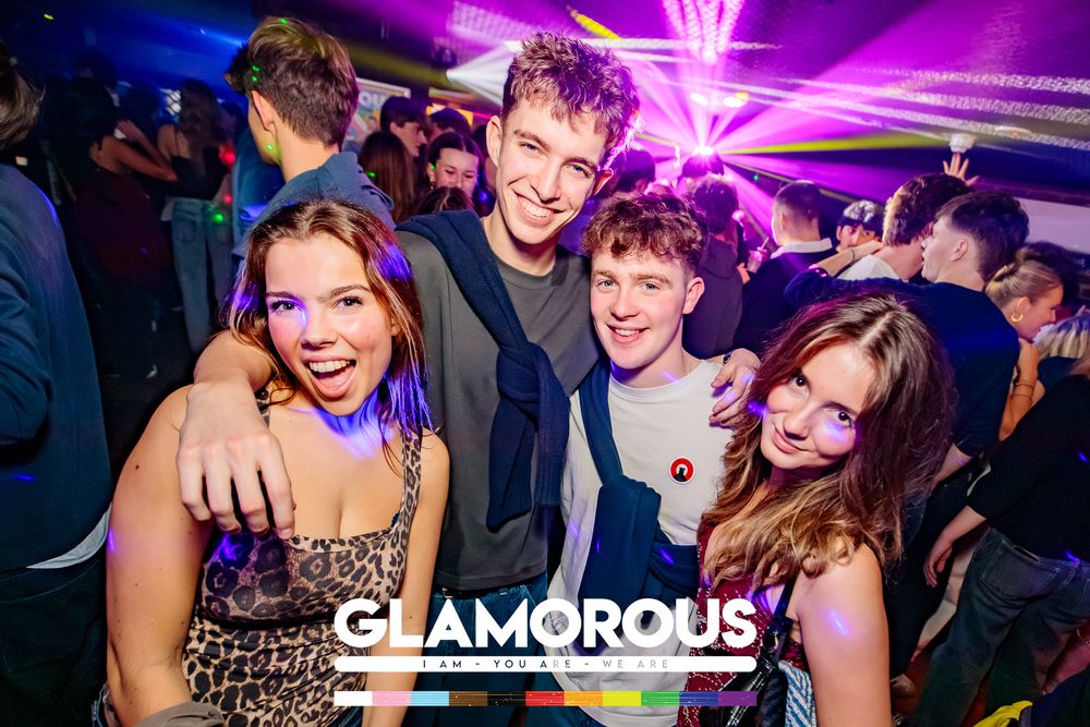 Group celebrating at a nightclub with vibrant purple lighting and dance floor atmosphere.