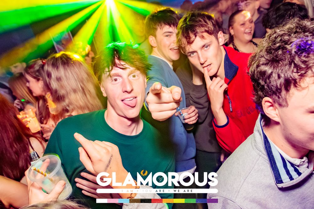 Energetic crowd dancing under green strobe lights at a nightclub party.