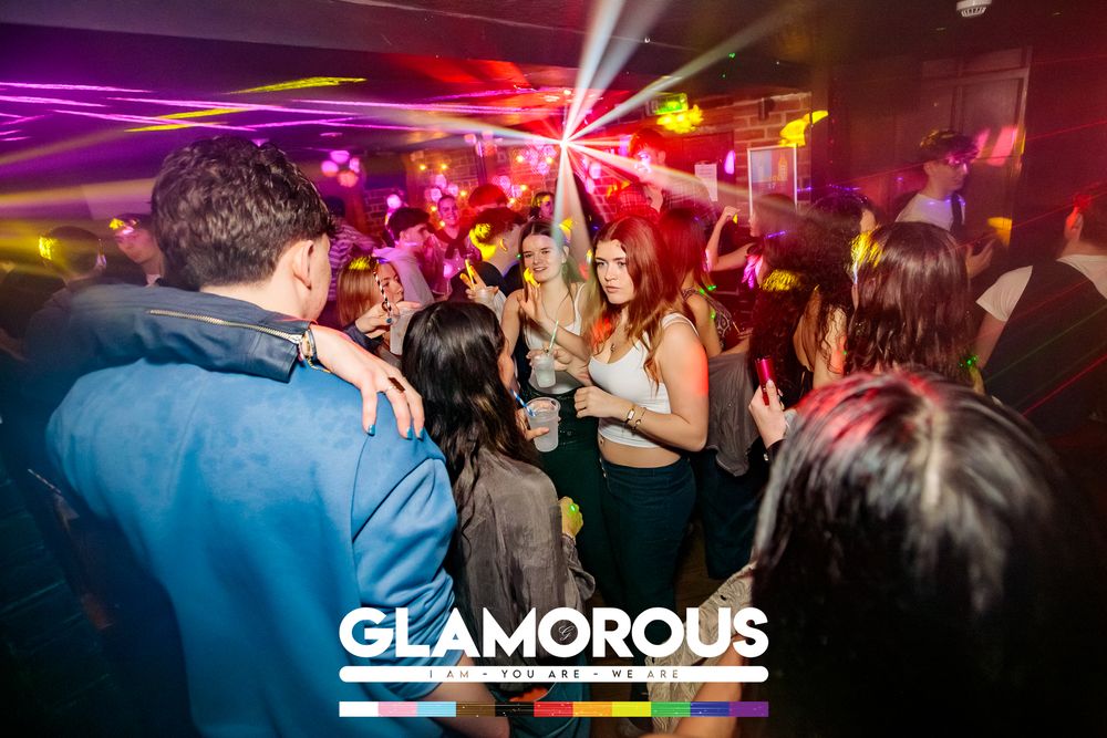 Packed dance floor with vibrant purple and red lighting at Glamorous nightclub.