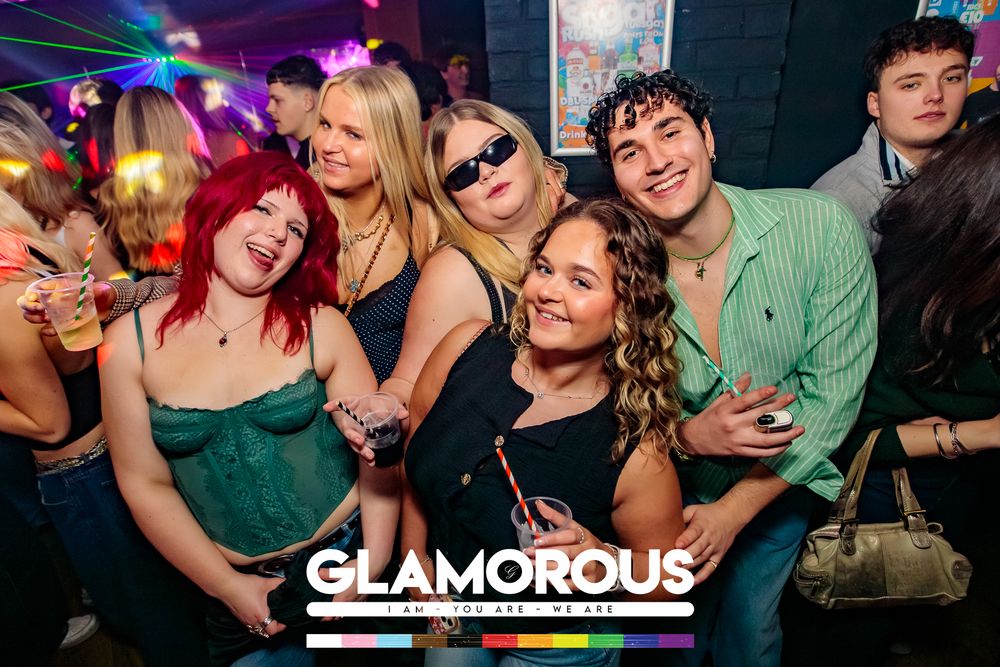 Group of party-goers having fun under colorful club lighting at Glamorous venue.