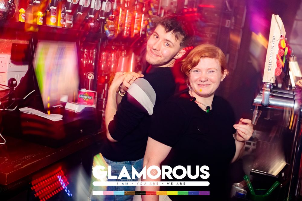 Nightclub scene with vibrant red and purple lighting showing people dancing and socializing at a party.