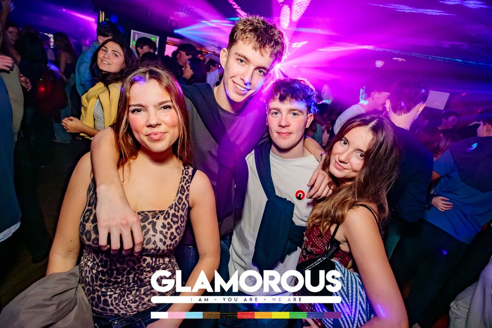 Crowded nightclub with purple lighting and party atmosphere showing people enjoying themselves.
