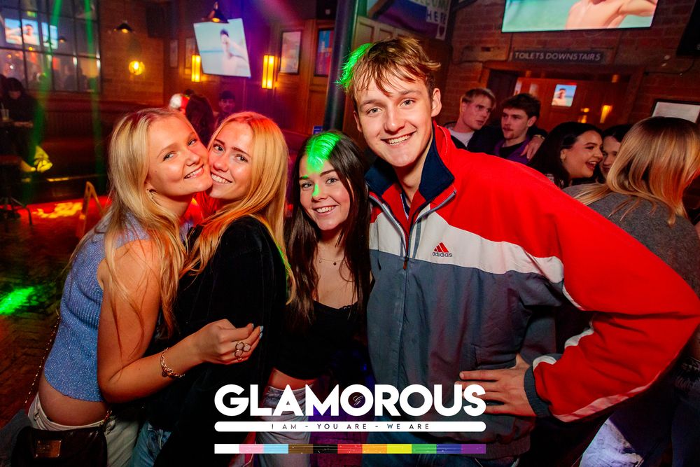 Lively bar scene with colorful lighting and groups of people socializing.