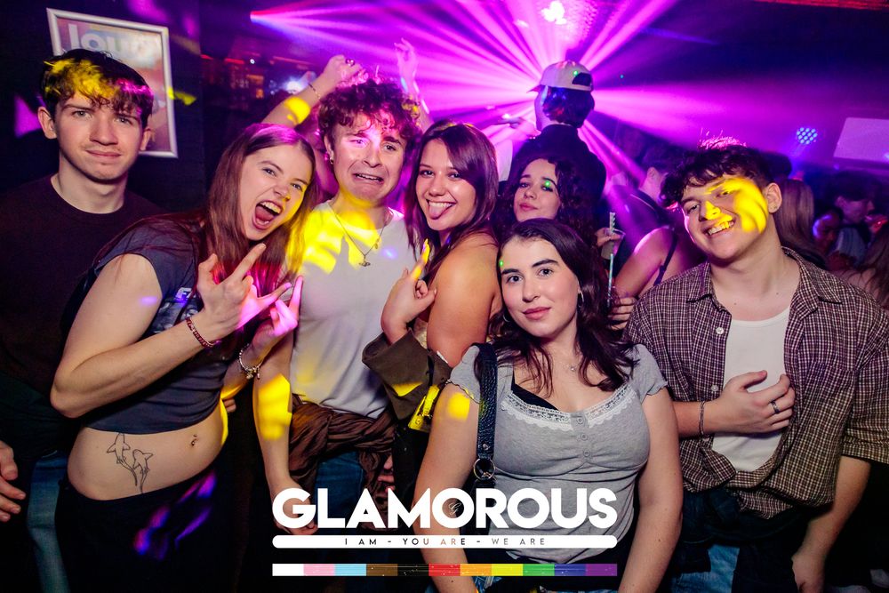 Energetic nightclub scene with purple lighting and packed dance floor.