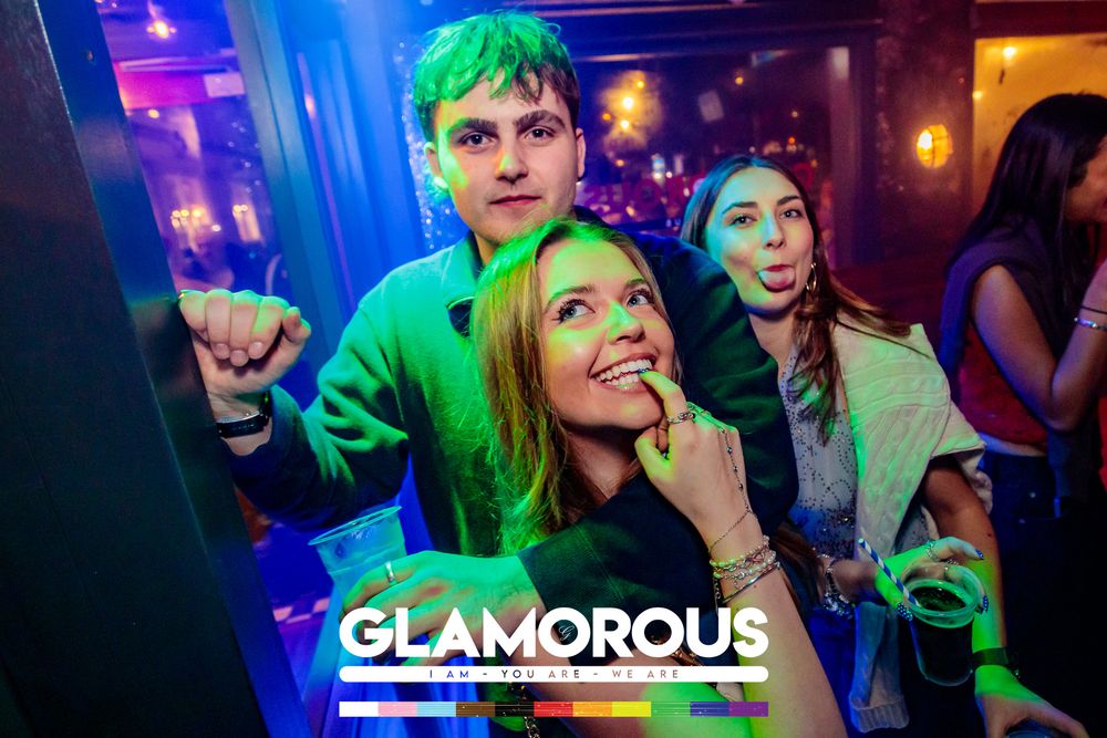 Nightclub interior with blue and green lighting effects showing partygoers on the dance floor.