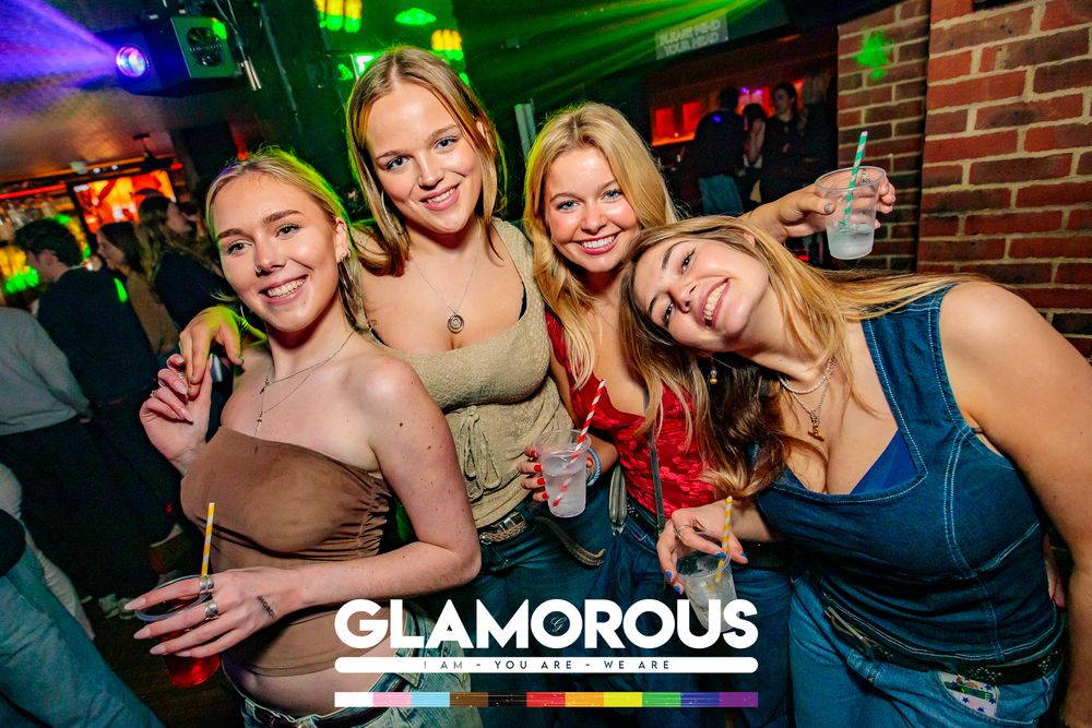 Friends enjoying drinks and smiling at a nightclub with purple lighting.