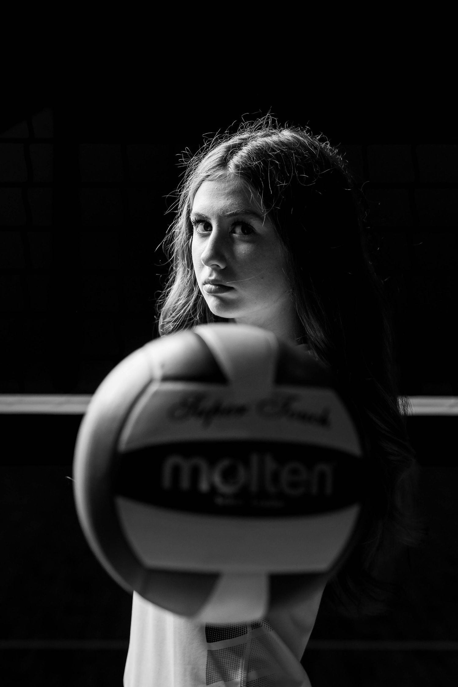 A dramatic black and white portrait series showing a volleyball player's face partially obscured by the ball.