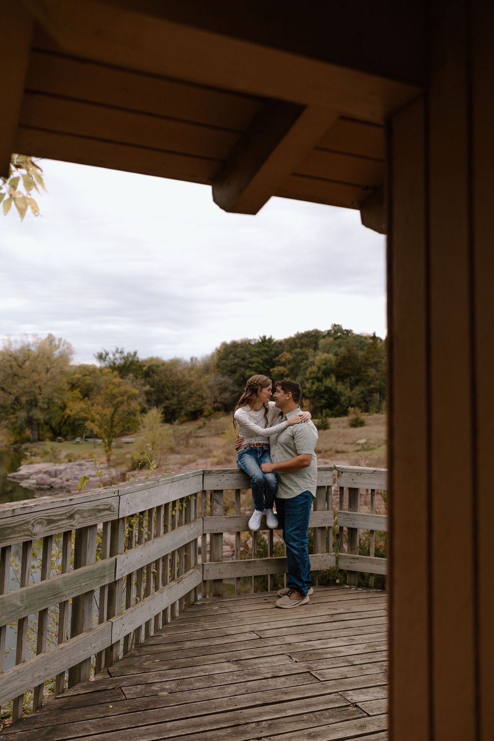 A couple shares an intimate moment on a wooden boardwalk overlook surrounded by autumn desert landscape.