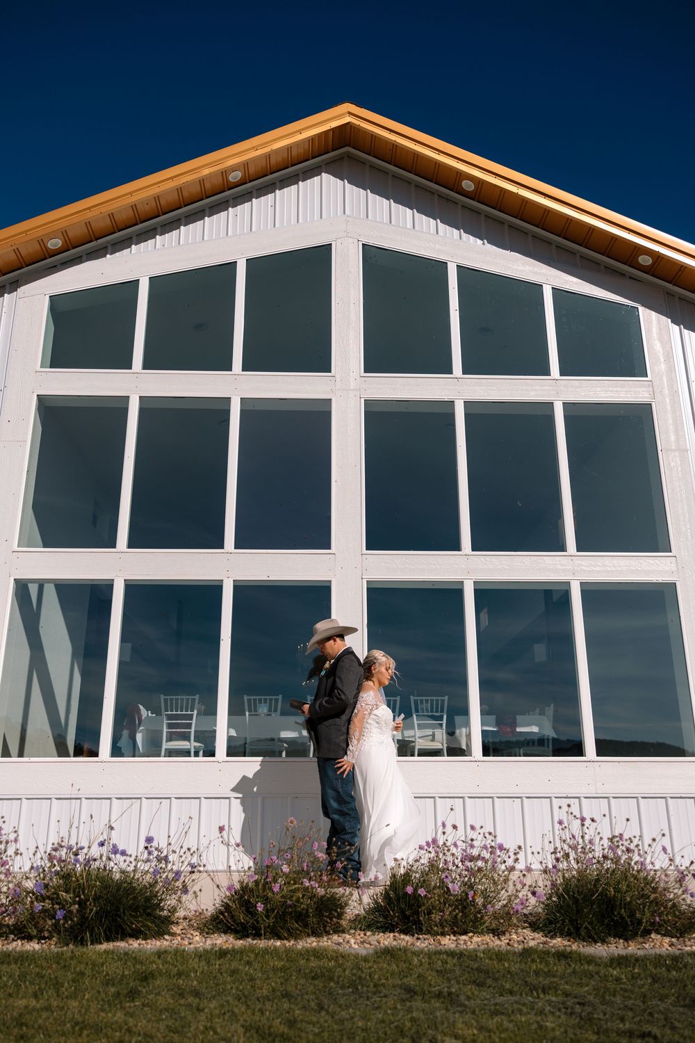 A panoramic sequence showing a couple embracing against a modern white building with large windows at sunset.