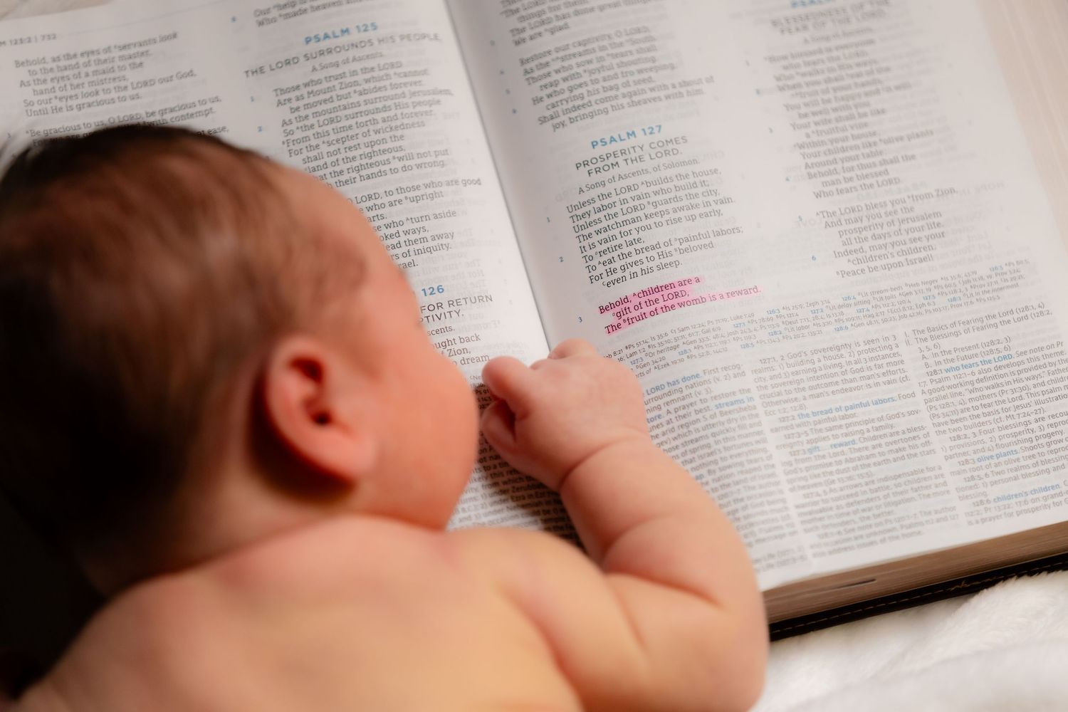 A newborn reading the bible from the book of Psalms.