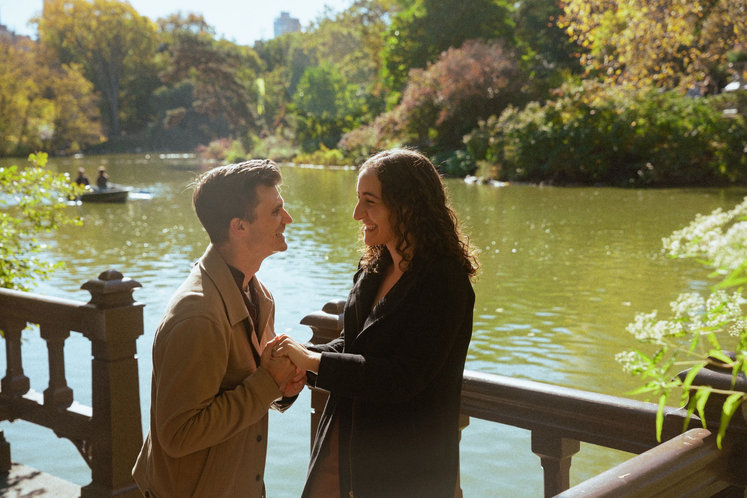 A tender moment between two people sharing an emotional conversation by a lake with autumn foliage.