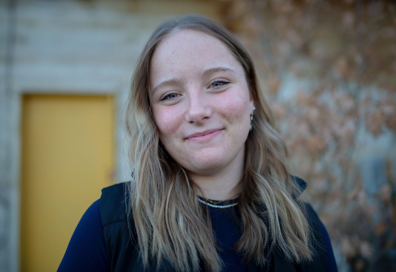 A graduating high school senior smiles in a senior photo session in Idaho. She's casual and relaxed at Webb Garden Center in Twin Falls.