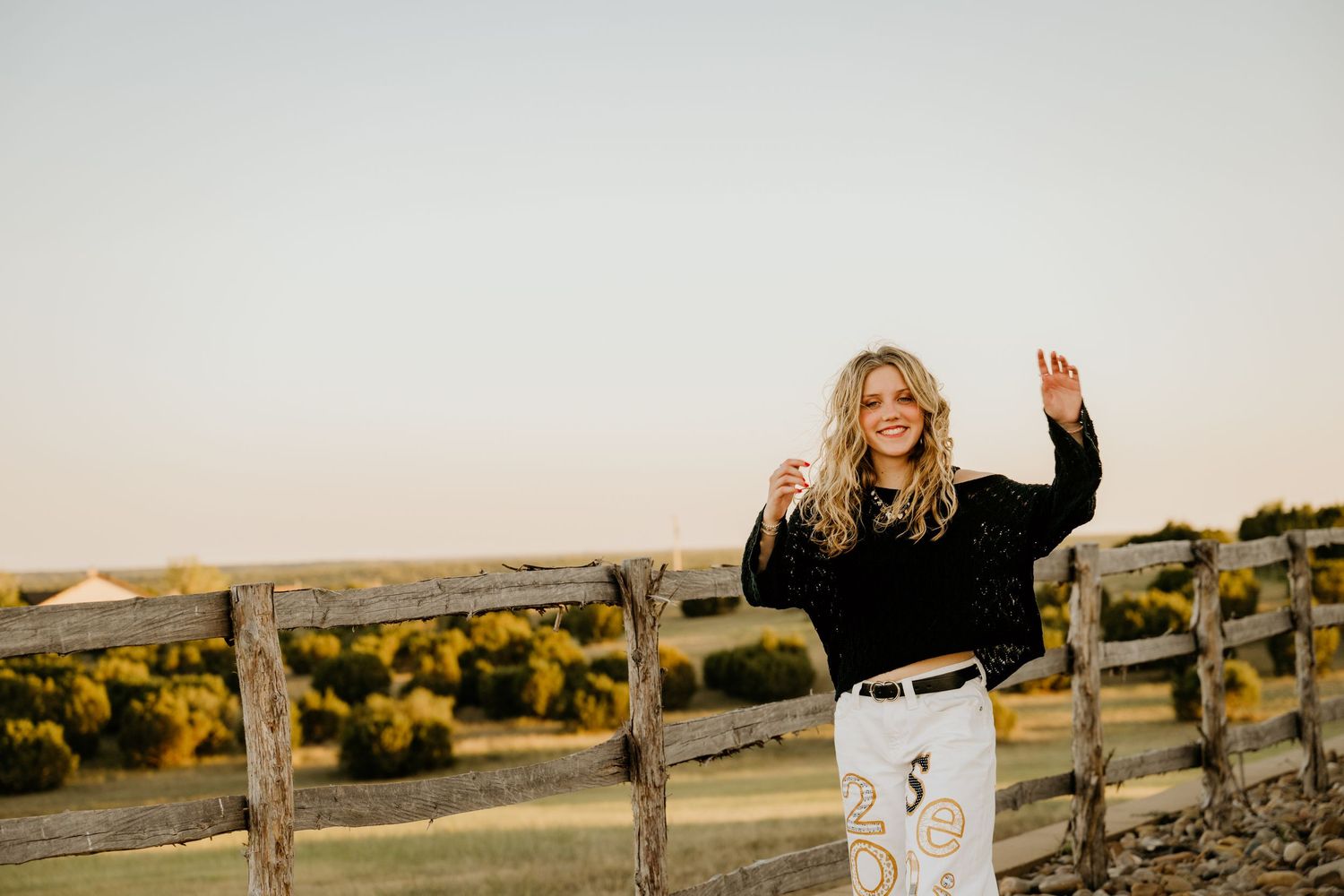 Rustic wooden fence stretches across field during golden sunset.