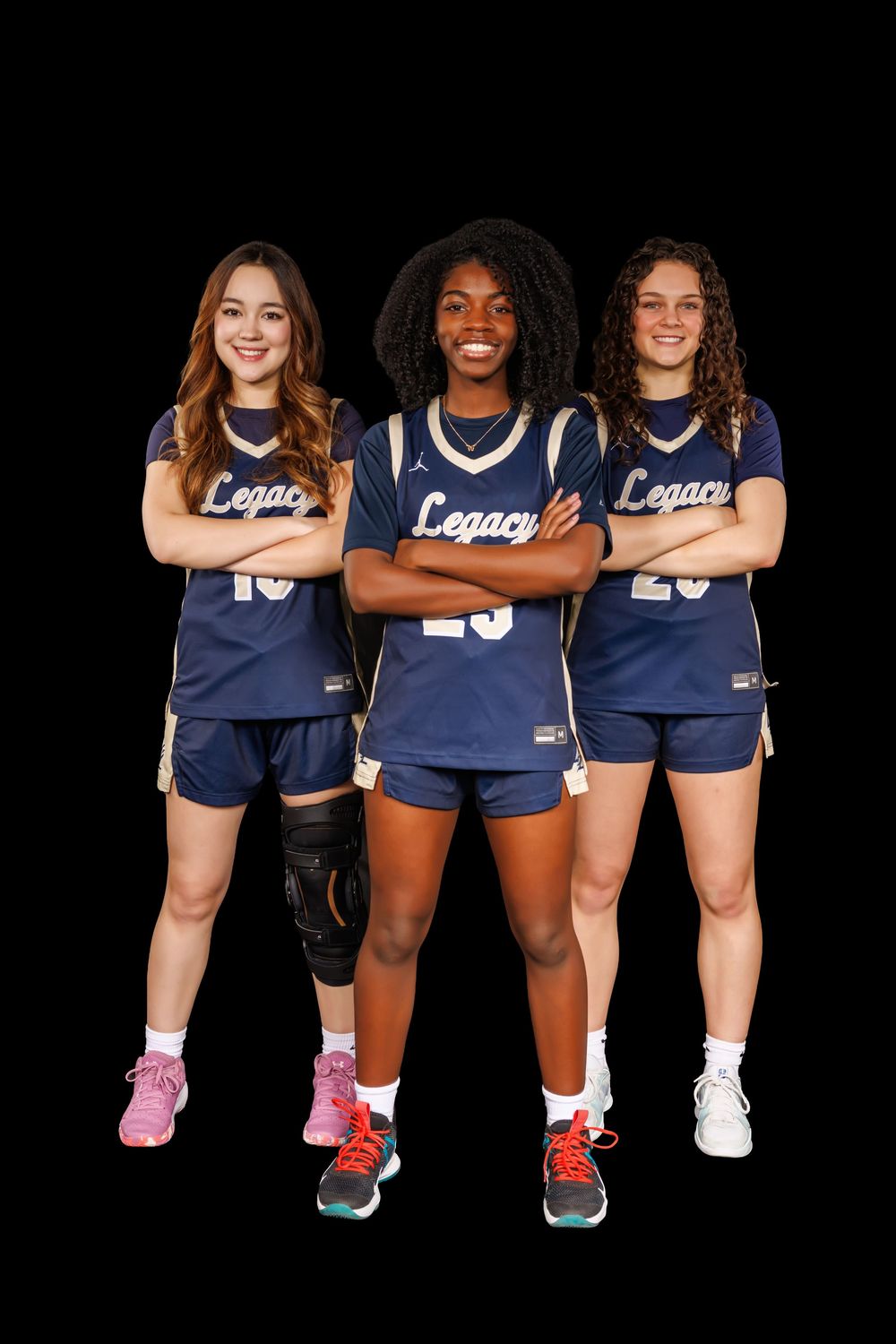 Three basketball players in navy Legacy uniforms sitting together showing team spirit.
