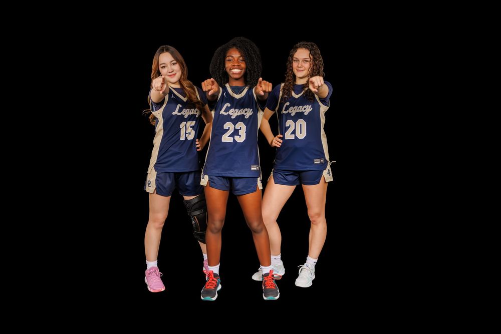 Three athletes in navy uniforms sit together on dark background for team photo.