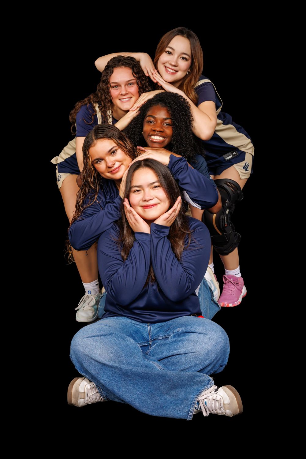 Athletes in navy jerseys pose playfully for team photos against black background.
