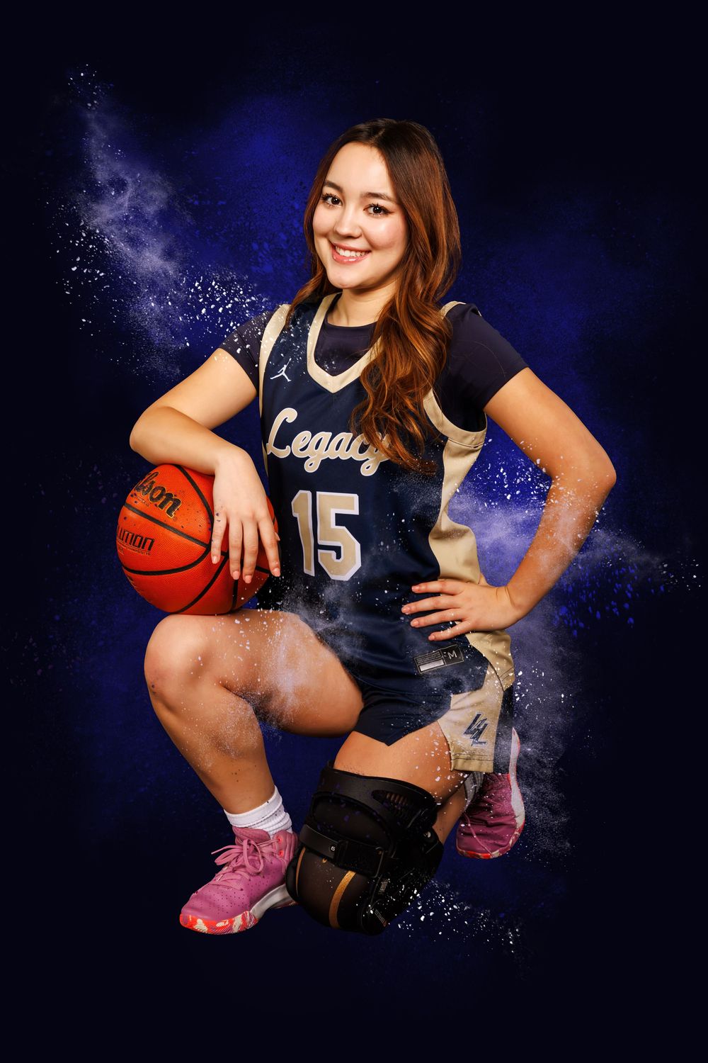 Basketball player in navy blue Legacy uniform poses with ball against dramatic blue backdrop.
