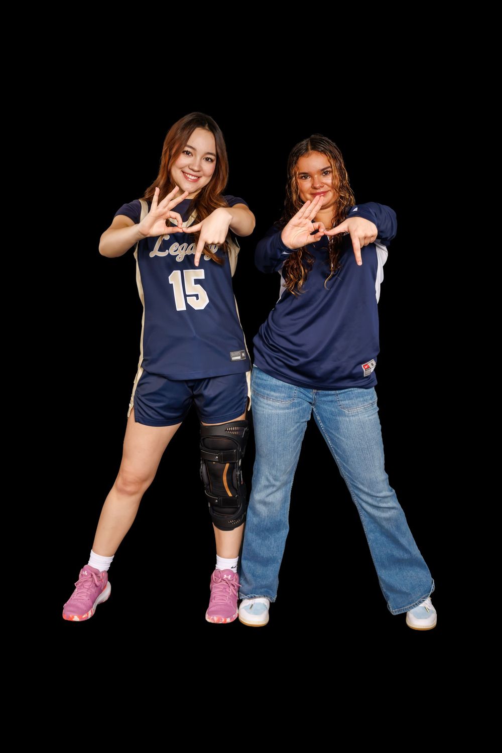 Two basketball players in navy uniforms posing together against black background.
