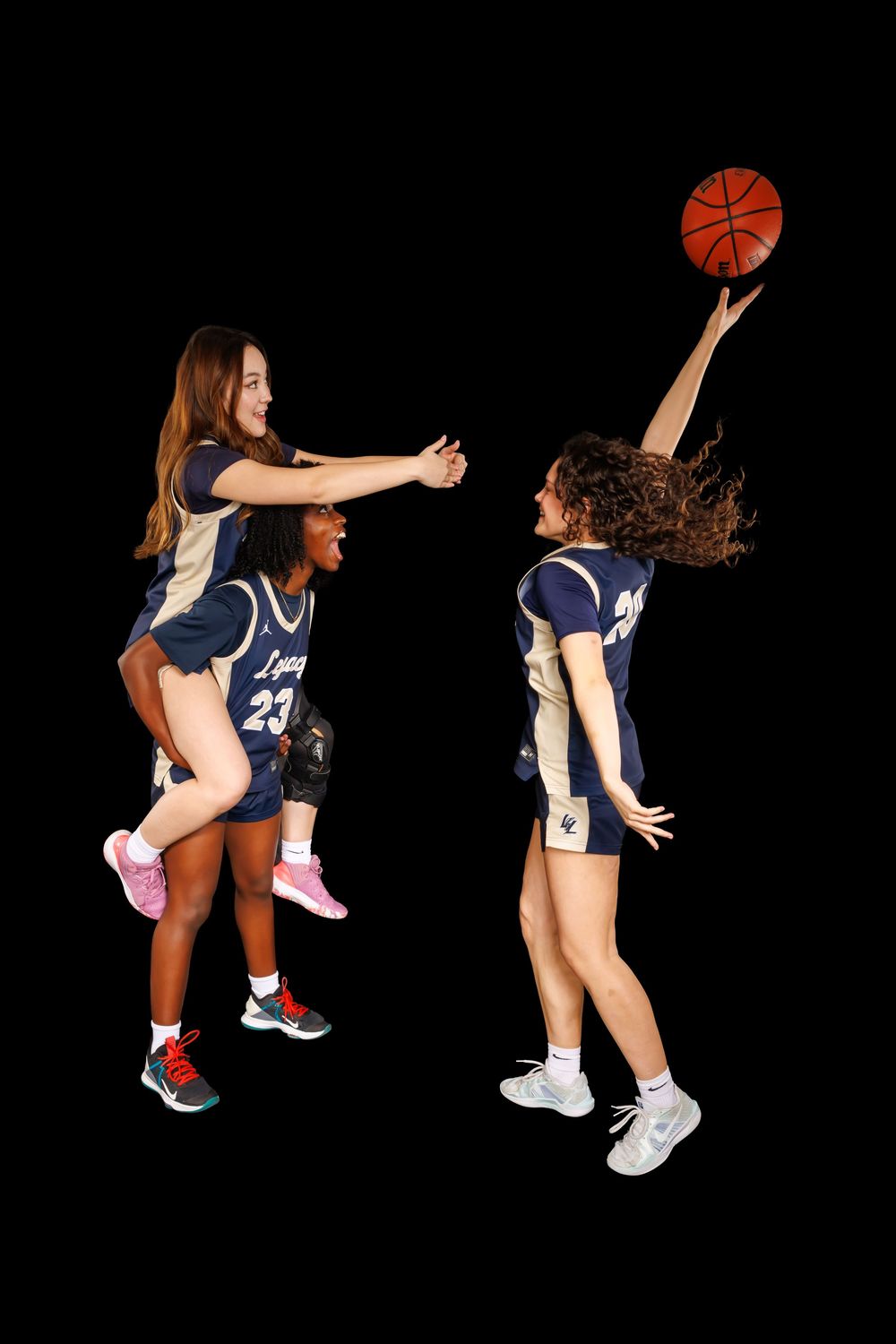 Athletes in navy uniforms jumping and playing with basketball against dark backdrop.