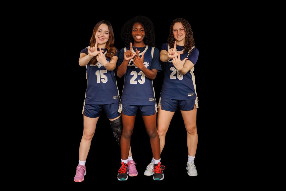 Group of basketball players in navy uniforms smiling and posing with basketballs.