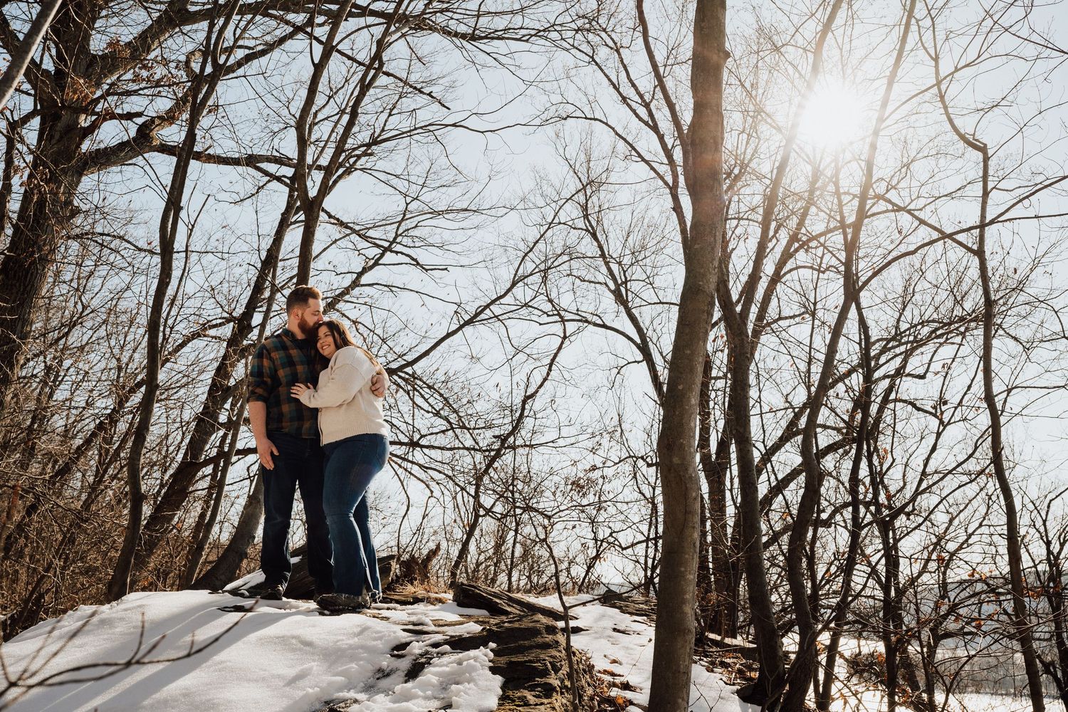 A couple embraces during a winter engagement photo session among bare trees for engagement photoshoot in Pequea, PA in Lancaster county.