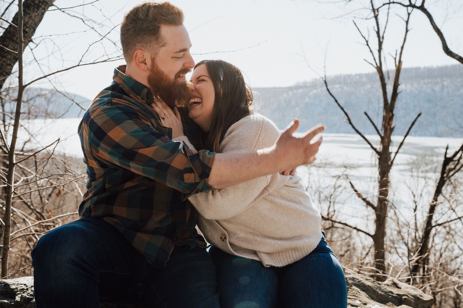 A couple shares a joyful moment while taking a selfie together on a scenic overlook during autumn.