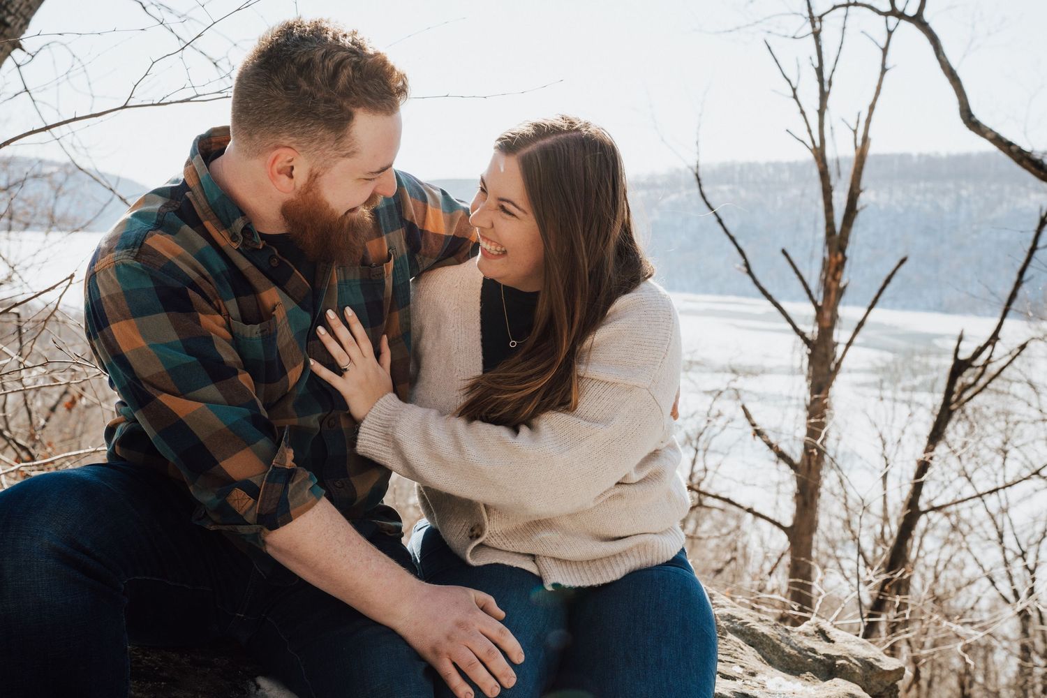 Couple embraces in a snowy winter landscape in the background for engagement photoshoot in Pequea, PA in Lancaster county.