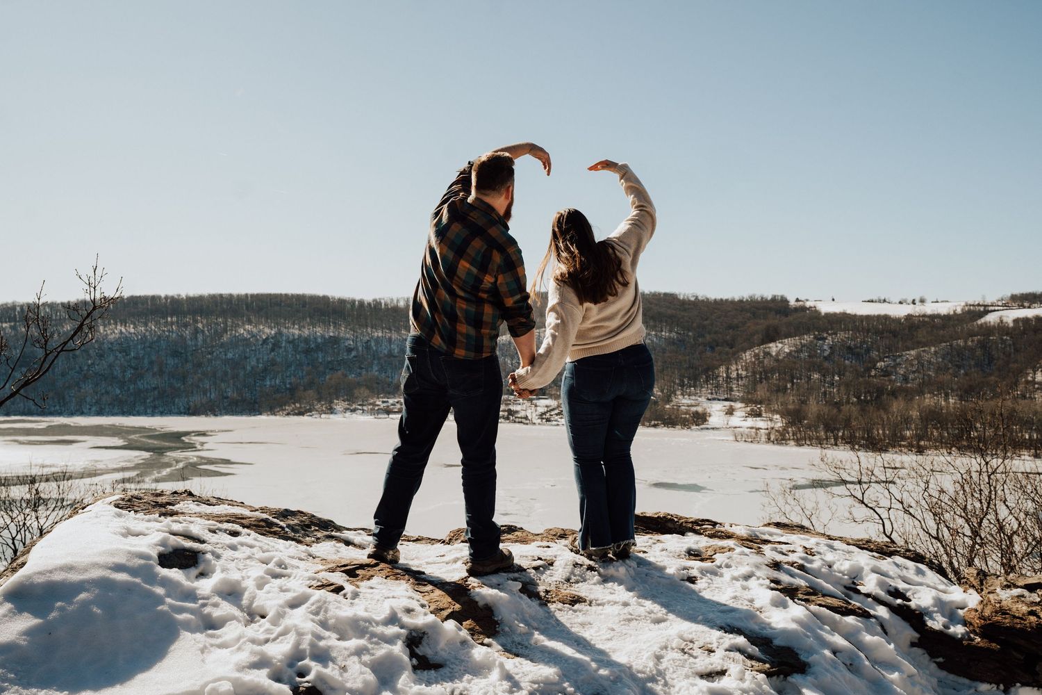 A couple stands together on a snowy overlook with mountains for Romantic winter engagement photo session in Lancaster County, Pequea, PA