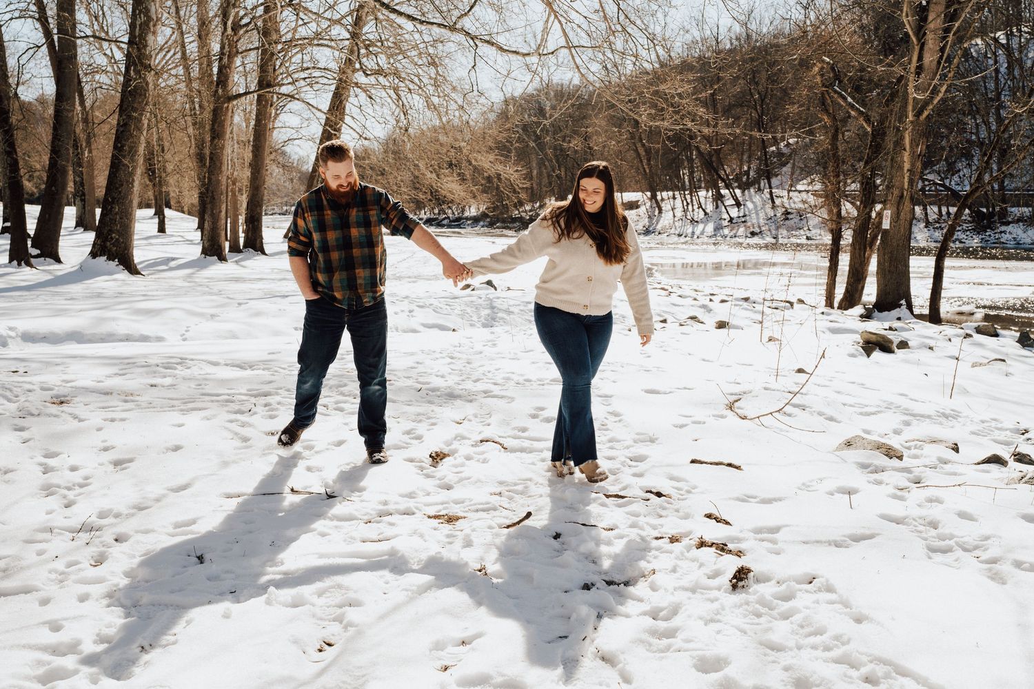 Romantic winter engagement photo session with couple walking holding hands with snowy background in Lancaster County, Pequea PA.