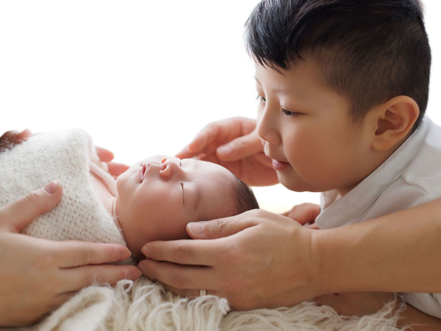 Newborn baby being gently held and cradled in multiple tender moments against white background.