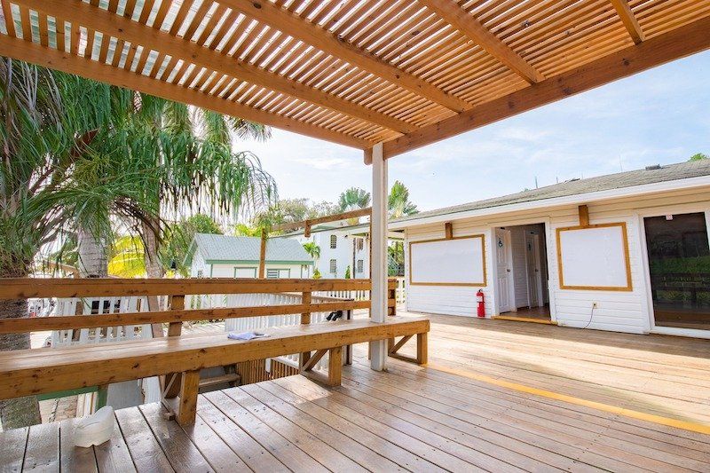 Wooden deck with pergola and bench seating overlooking waterfront views.