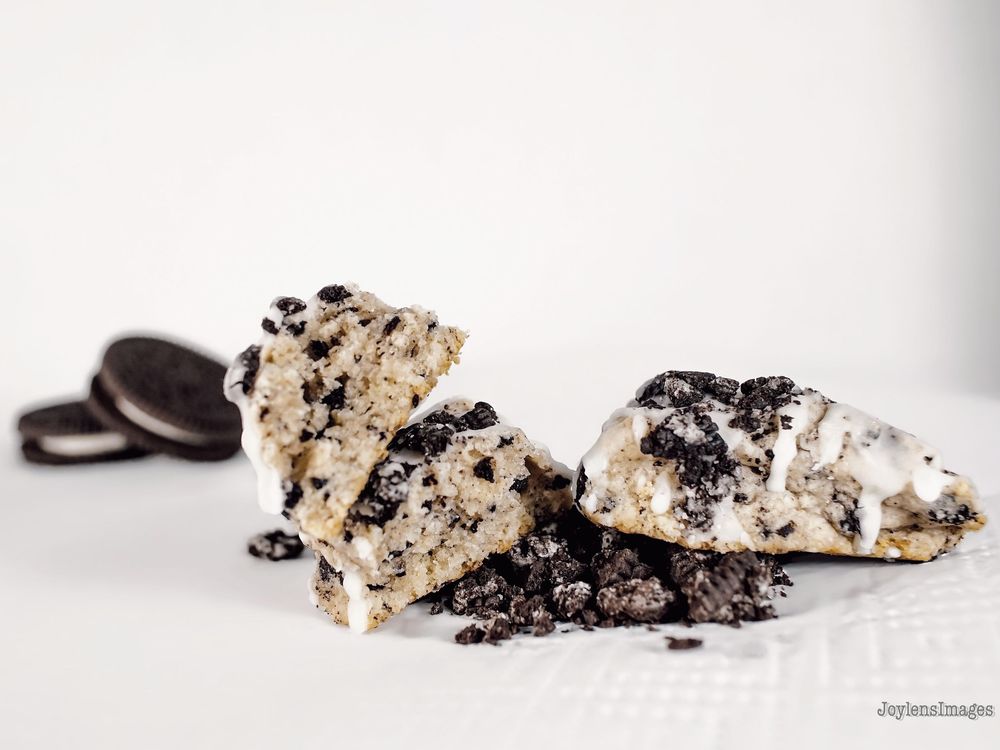 Cookies and cream ice cream scoops with crushed Oreo cookies and vanilla swirls on white background.