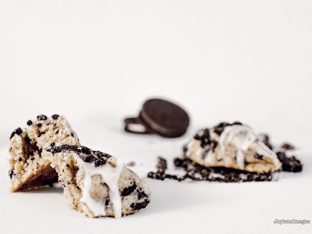 A row of chocolate-drizzled coconut macaroon cookies arranged in a line on a white surface.