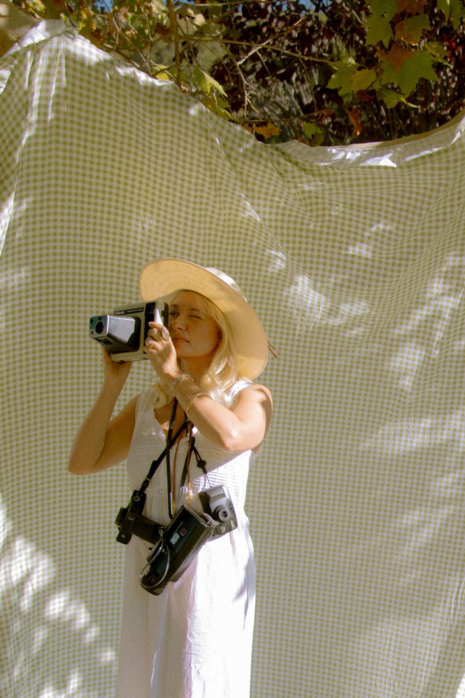 A sequence of black and white photos shows someone in a white dress taking photographs with a vintage camera.