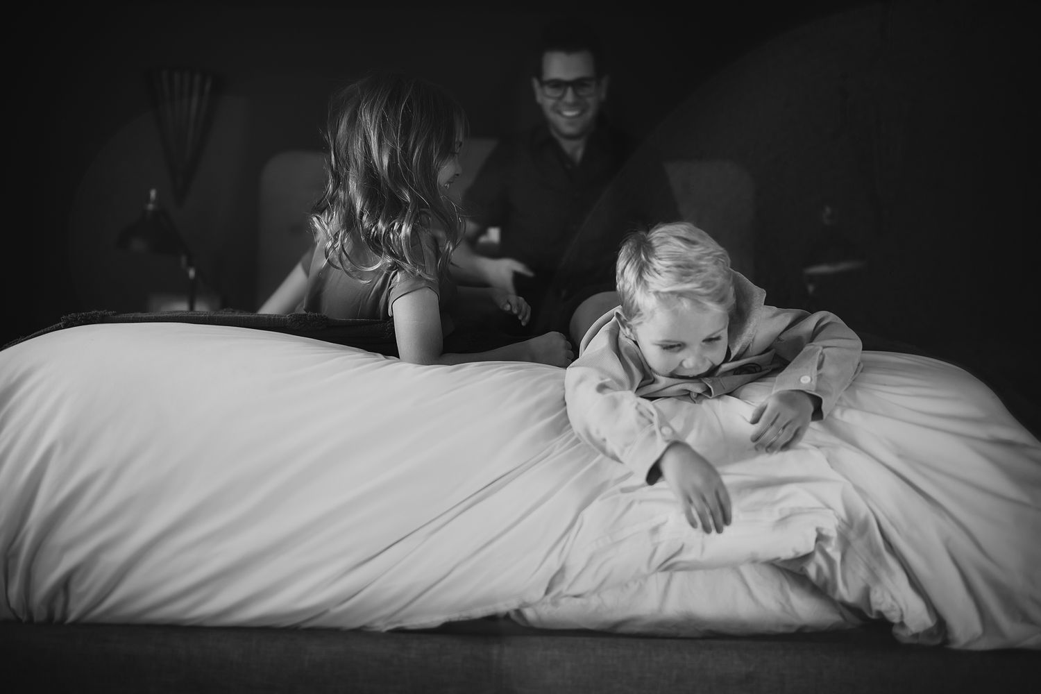 A black and white photo series showing a person relaxing and reading on a white bed.