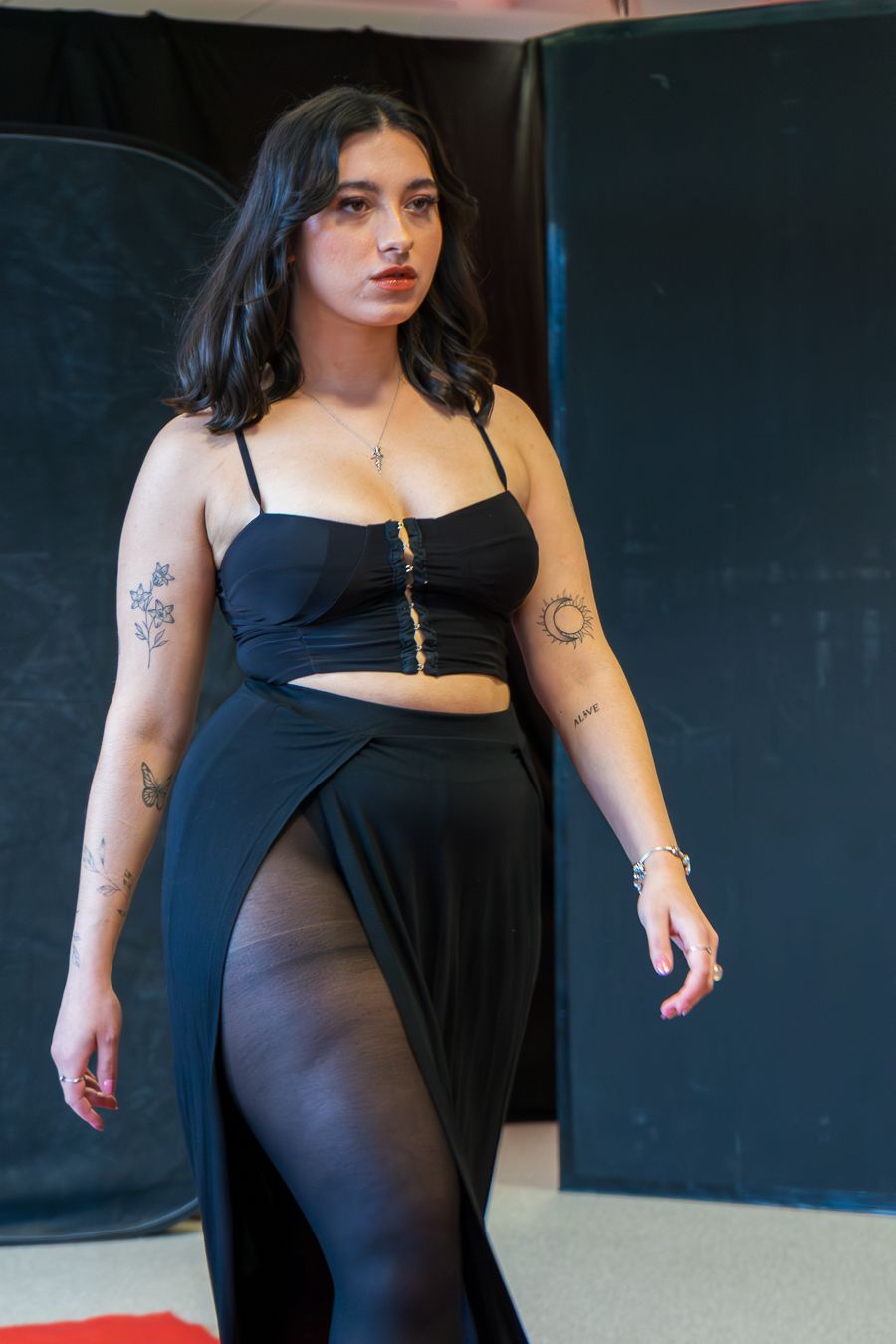 A person in a black dress poses against a dark background in a series of artistic fashion photographs.