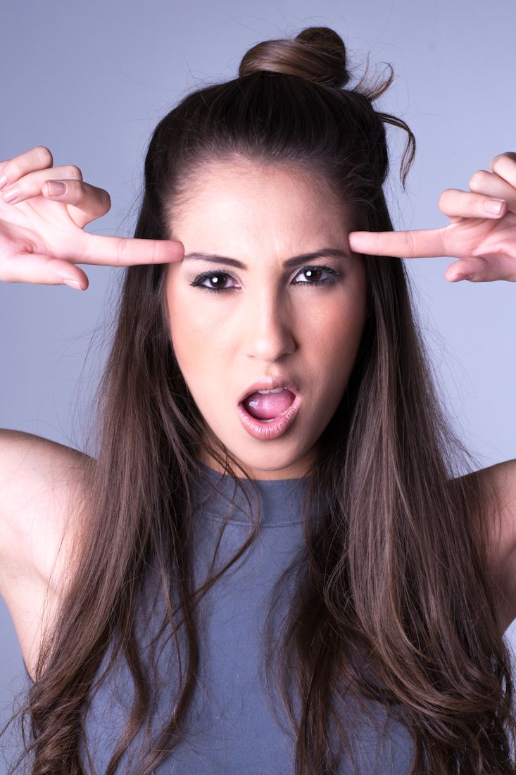 Playful portrait series showing model making faces and gestures against blue background.