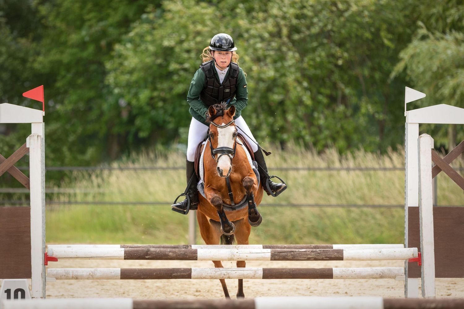 Horse and rider clearing jumps during equestrian competition.