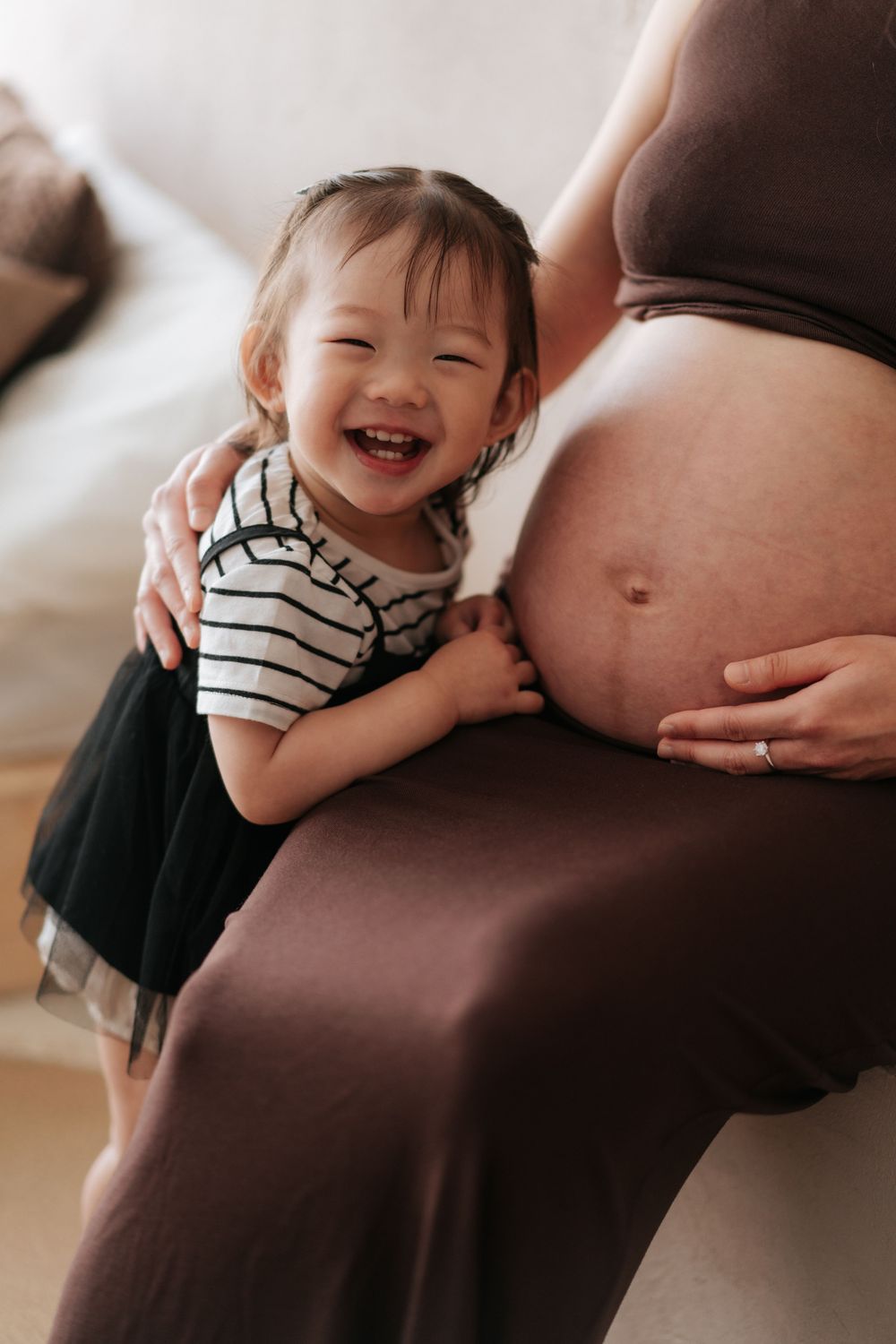 A joyful child in striped shirt touches a pregnant belly while smiling warmly in a series of candid moments.