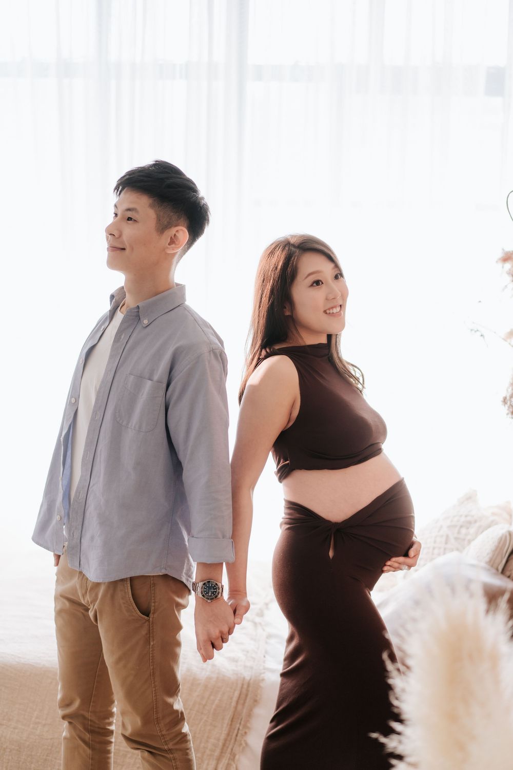 A couple in casual attire dances and laughs together in a bright, airy studio with white decor.
