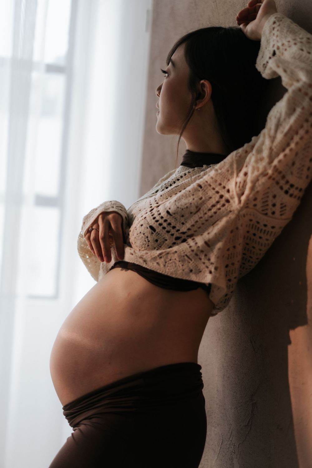 Artistic maternity photo series showing pregnant belly in black and white with delicate lace details.