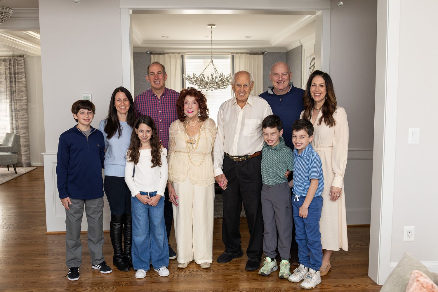 A large family gathering poses together in a bright, modern interior hallway.