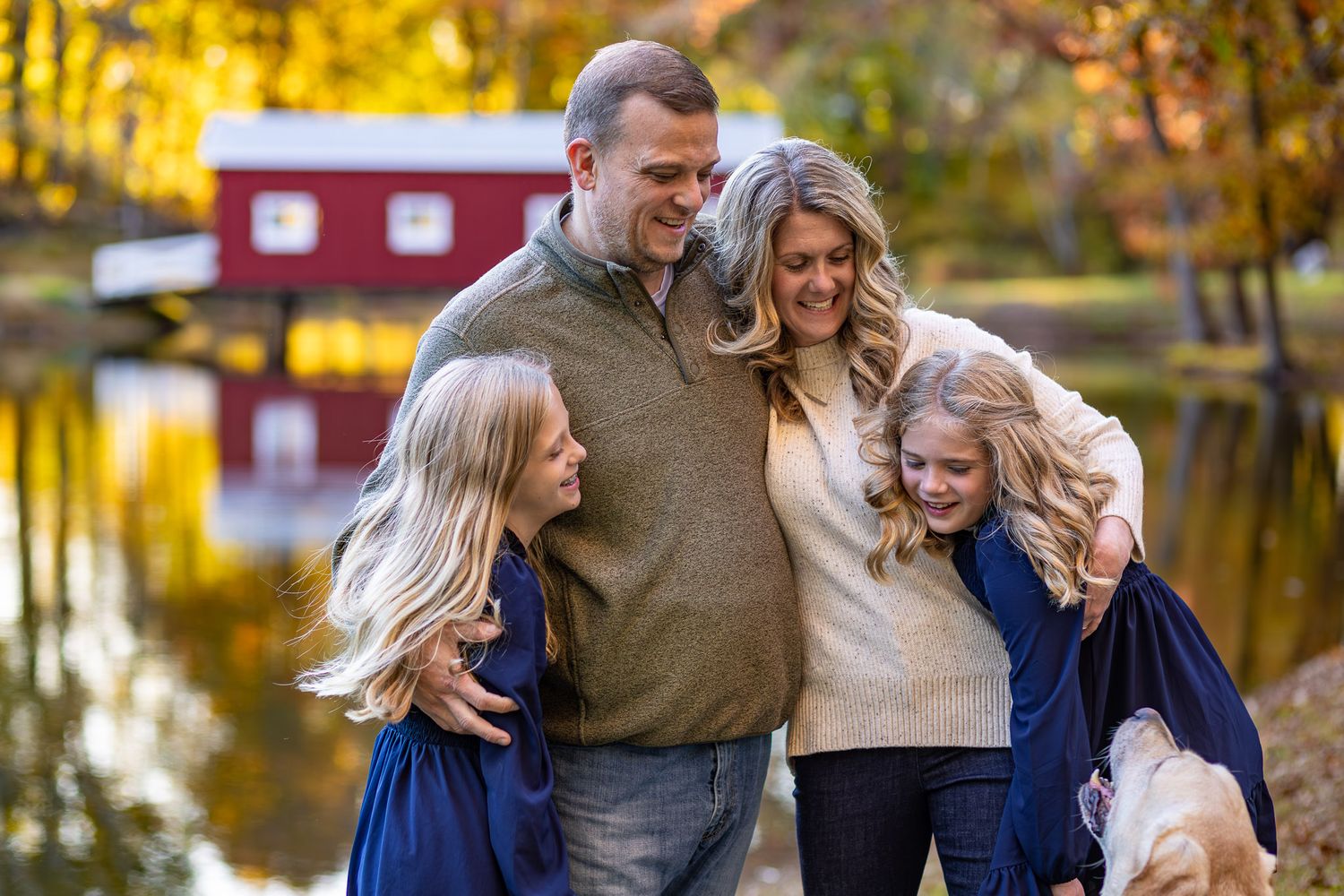A family shares joyful moments together during an autumn photoshoot with golden foliage in the background.