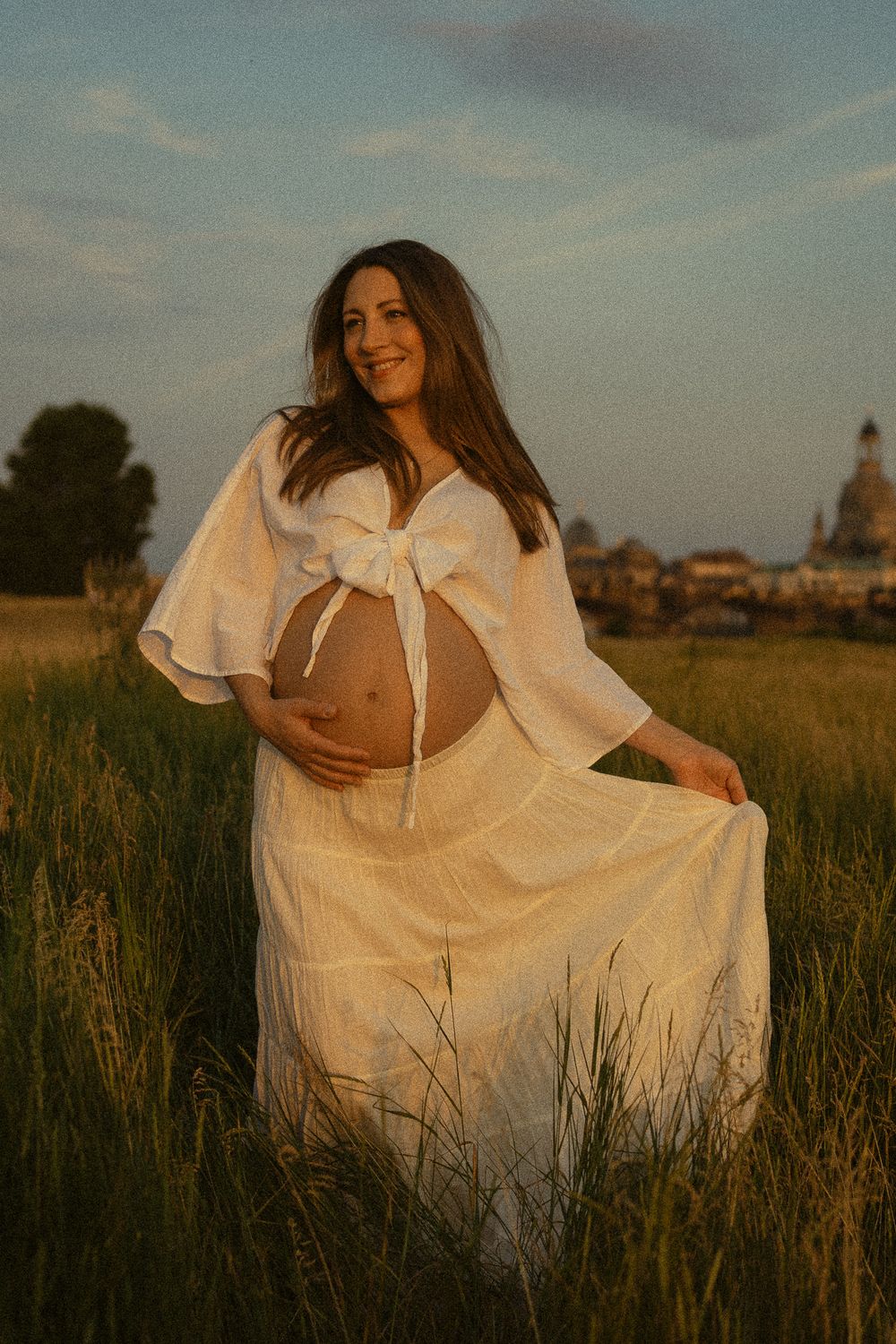 Nostalgisches Portrait Fotoshooting - Schwangere Frau schwingt Rock über die Elbwiese in Dresden zum Sonnenuntergang